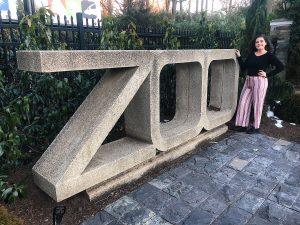 Elena Iacono standing next to a concrete zoo sign