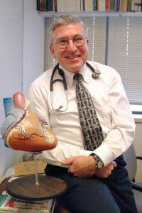 Jim Ross posing with model of a heart