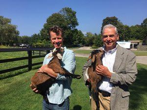 Peter Borden and George Saperstein pose for a picture holding goats
