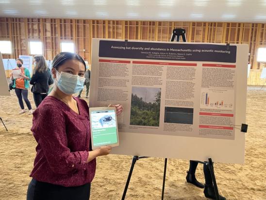 Vanessa Indeglia, V23 student at Cummings School of Veterinary Medicine standing next to her poster presentation on "Understanding the Misunderstood"