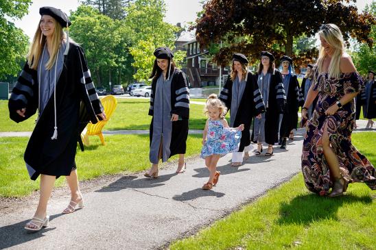 graduate students in their caps and gowns walking to the ceremony