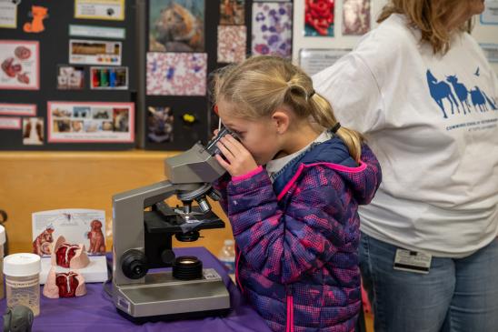 A young individual looks into a microscope.