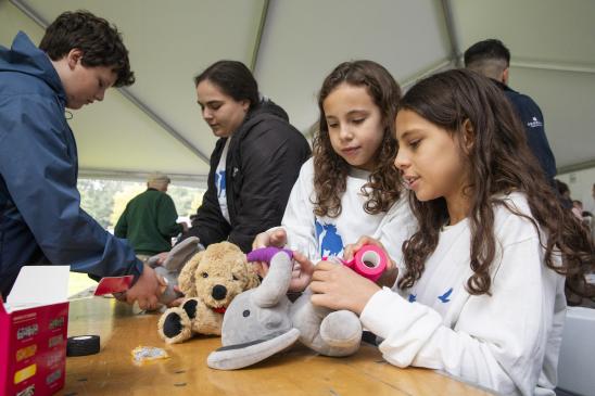 Two young individuals and their stuffed animals. Two middle school aged individuals also at the table.