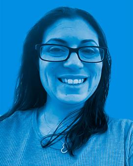 Jennifer Keefe standing outside smiling with dark glasses and dark shoulder length hair. There is a blue filtered background.