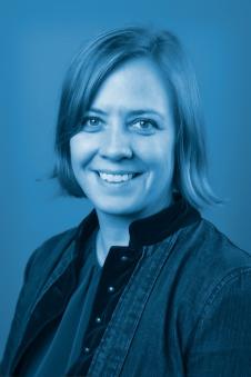 Fair Vassoler smiling. Photo has a blue tinted background.