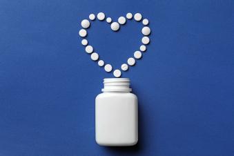Bottle and heart of pills on color background. Photo: Adobe Stock | #264052563 | By New Africa
