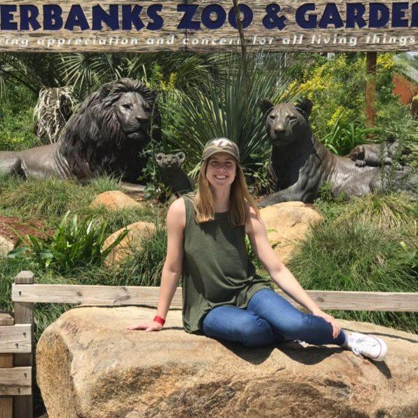 Alumni Casey Boyer in front of a zoo sign