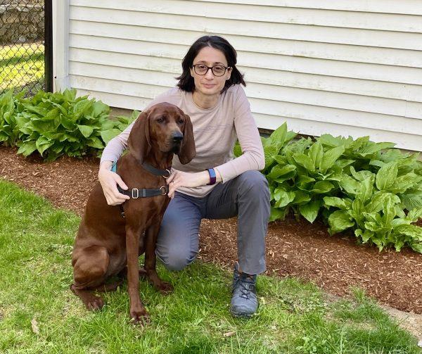 Andrea Varela-Stokes poses for a picture crouched next to her dog, Stella