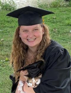 Kiersten Hartnagel wearing a graduation cap and gown holding her cat