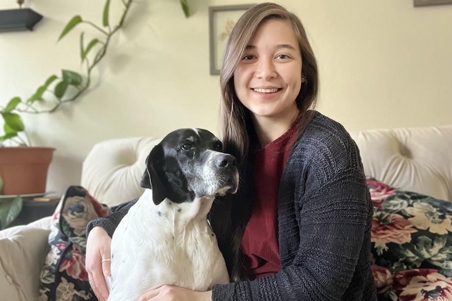 Young woman, Diana Chan, sitting on the couch holdinng her black and white dog, Alice