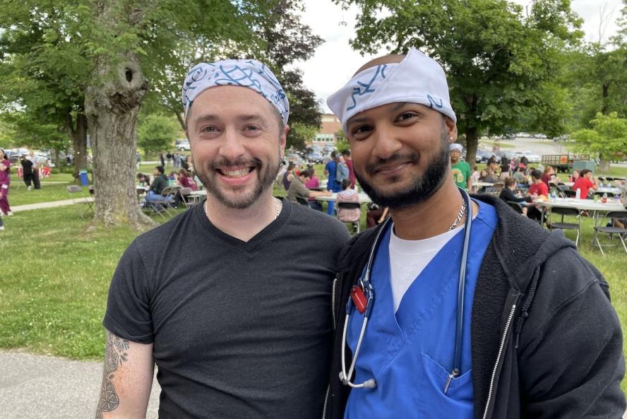 Two staff members with bandanas on their heads at a cookout. 