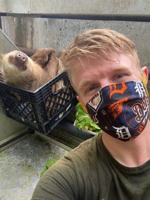 Peter Sonnega in a selfie with a sloth in a milk crate