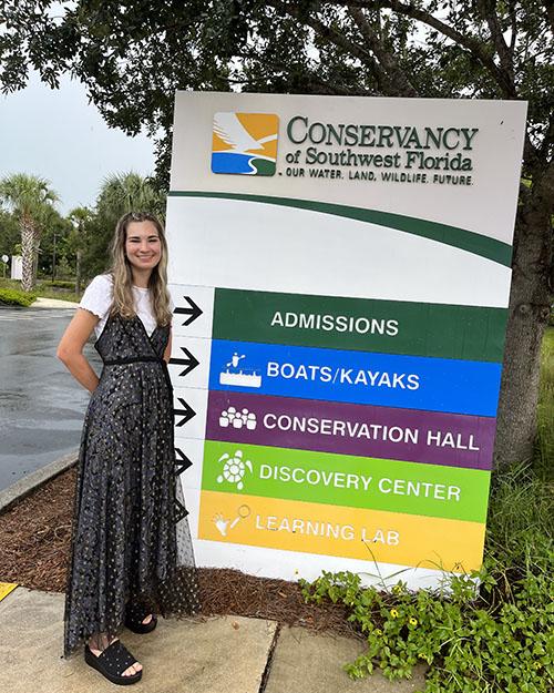 Emily Williams standing next to a large sign outdoors