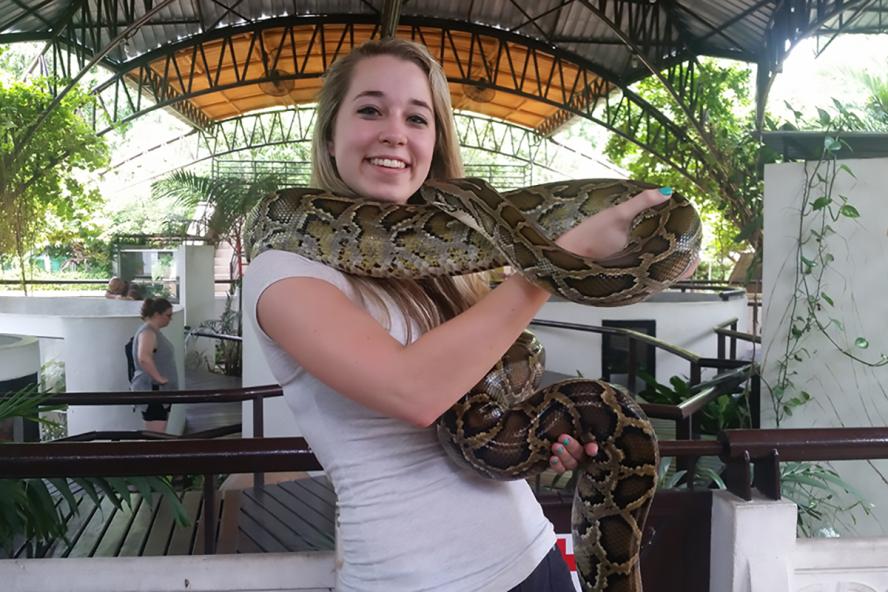 Jillian Morrell posing for photo with a large snack wrapped around her neck.