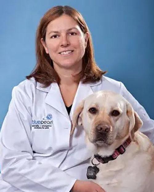 Leslie Schwarz, staff veterinarian, posing for photo with her white Labrador Retriever
