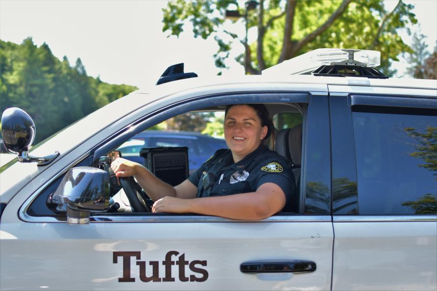 Female police officer in uniform sitting in a white SUV with her arm on the window. 