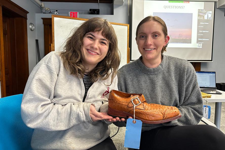 Two smiling women holding a confiscated crocodile leather shoe brought by USFWS agents