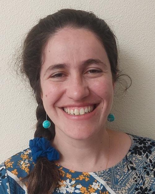 A smiling woman with brown hair braided to one side, wearing a floral shirt.