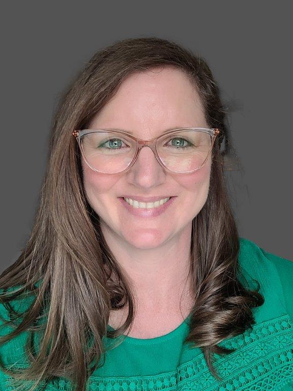 Brown haired women smiling wearing a green top and glasses.