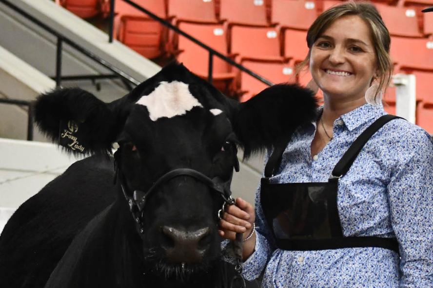 A woman in a casual blue shirt and jeans with a black and white cattle