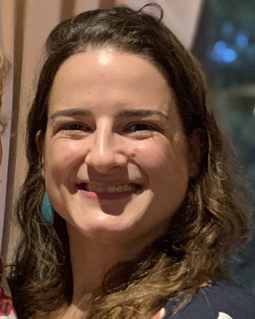 a smiling individual with long brown wavy hair