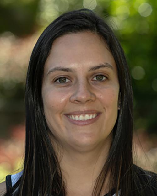 a smiling individual with long dark hair.