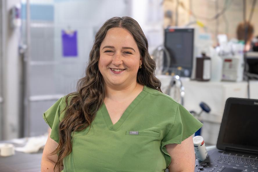 Person smiling and wearing green scrubs in the emergency and critical care room