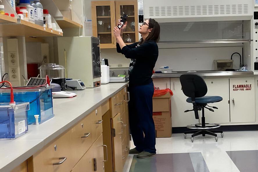 A person in a laboratory holding a piece of lab equipment.
