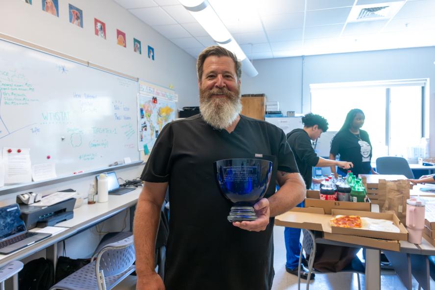 Person smiling, holding a blue crystal engraved award bowl.