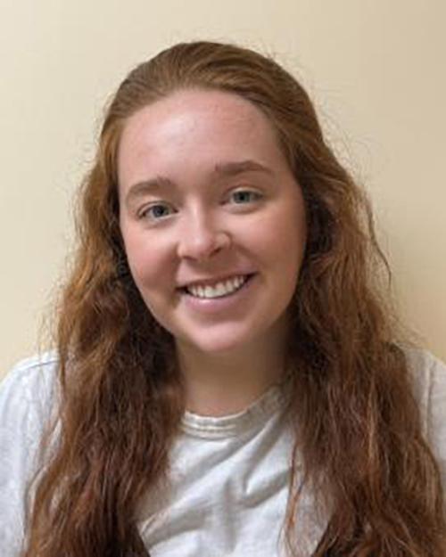Samantha Ladd, PsyD, Licensed psychologist for Tufts University Behavior Health. She has long red hair, is smiling and wearing a white shirt.