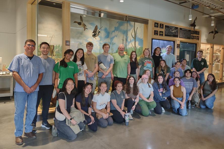 A group of individuals standing and kneeling smiling in a high school building.