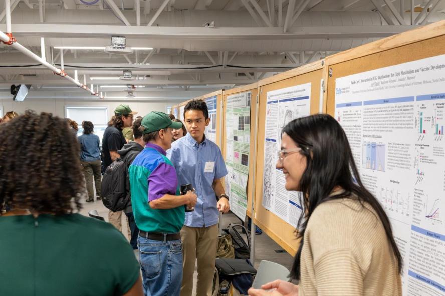 A crowd of people viewing research poster presentations.