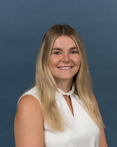 Alexandra Diamond has long blond hair. She is smiling and waring a white sleeveless blouse.