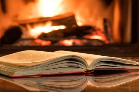 An open book in front of a fireplace.