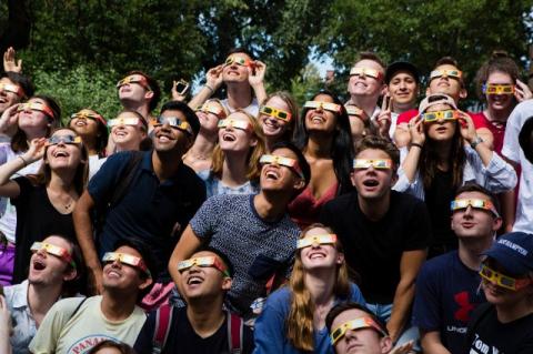 Young people with special glasses look upwards at the sky.