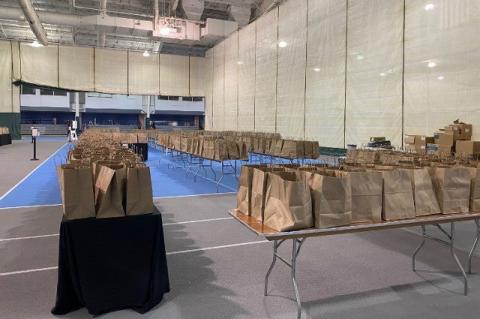 Rows of paper bags on tables in a gymnasium.