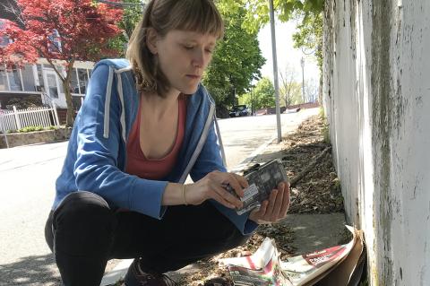 Marieke Rosenbaum Crouches examining a smart rat trap