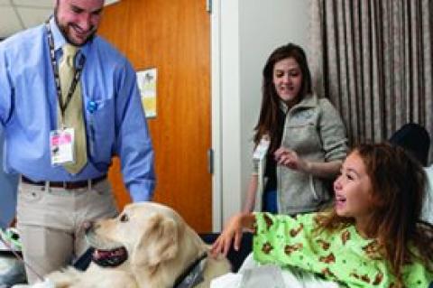 Connor O'Boyle, MG17, M21, and his three-year-old golden retriever, Dublin, volunteer their time visiting patients at the Floating Hospital for Children at Tufts Medical Center