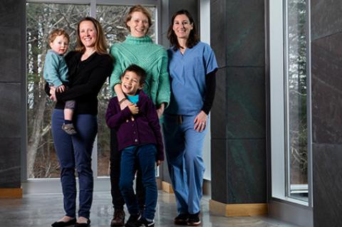 Mothers Megan Mueller, Assistant Professor of Clinical Sciences, with her son Oliver, 2, Marieke Rosenbaum, Research Assistant Professor of Infectious Disease and Global Health, with her son Zee, 7, and Annie Wayne, Assistant Professor of Clinical Sciences, pose for a group photo in the Agnes Varis Campus Center at Cummings School of Veterinary Medicine.
