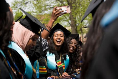 happy graduates wave to each other at commencement