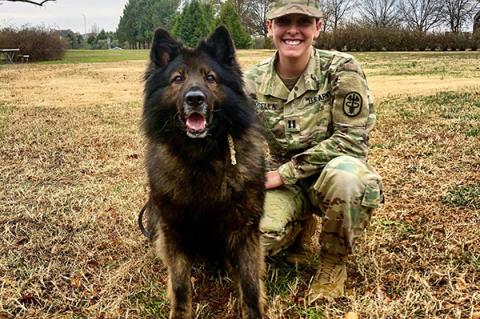 Major Kristen Arango kneels next to a military service dog named Terry