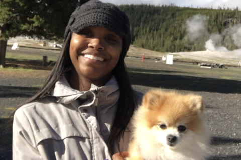 Katelin Jackson in a hat holding a pomeranian dog.