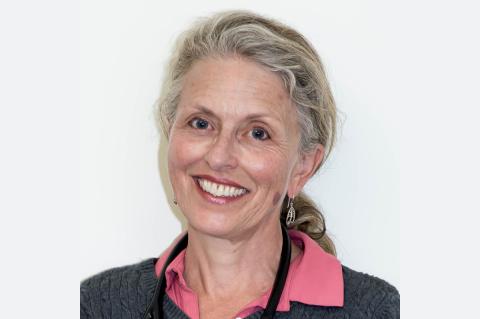 Smiling women with blonde and grey hair, pink blouse and grey sweater