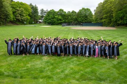 a large group of individuals on commencement day posing for a group photo in their caps and gowns.