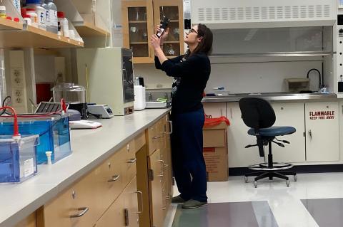A person in a laboratory holding a piece of lab equipment.