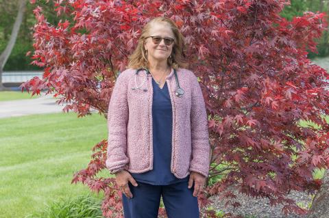 Professor Emeritus Cynthia Leveille-Webster standing outside in front of a Japanese maple tree.