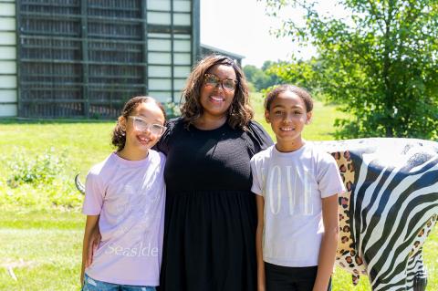 Tracey Glover and her two children standing outside on a sunny day.