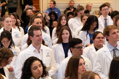 Veterinary students standing in white coats reciting an oath.