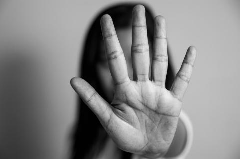 Black and white photo of woman with outstretched palm in front of her face